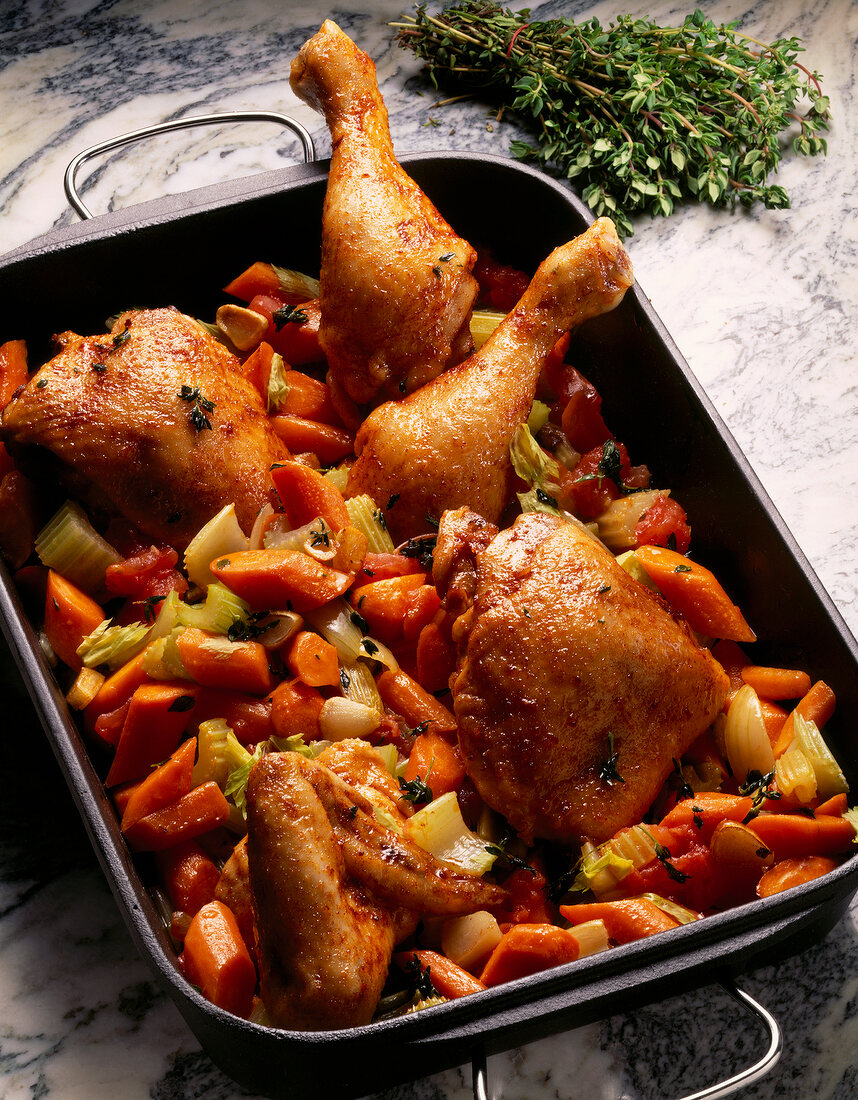 Chicken rotisserie with carrots and celery in serving dish