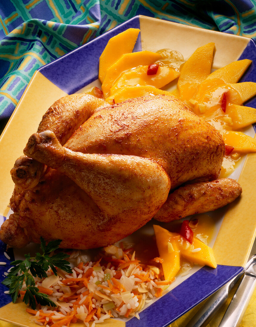 Close-up of stuffed chicken with vegetable rice, mango sauce and parsley on plate