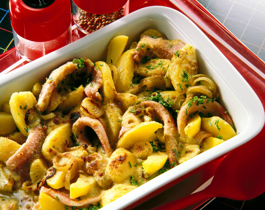 Close-up of young herring and potato bake on serving dish