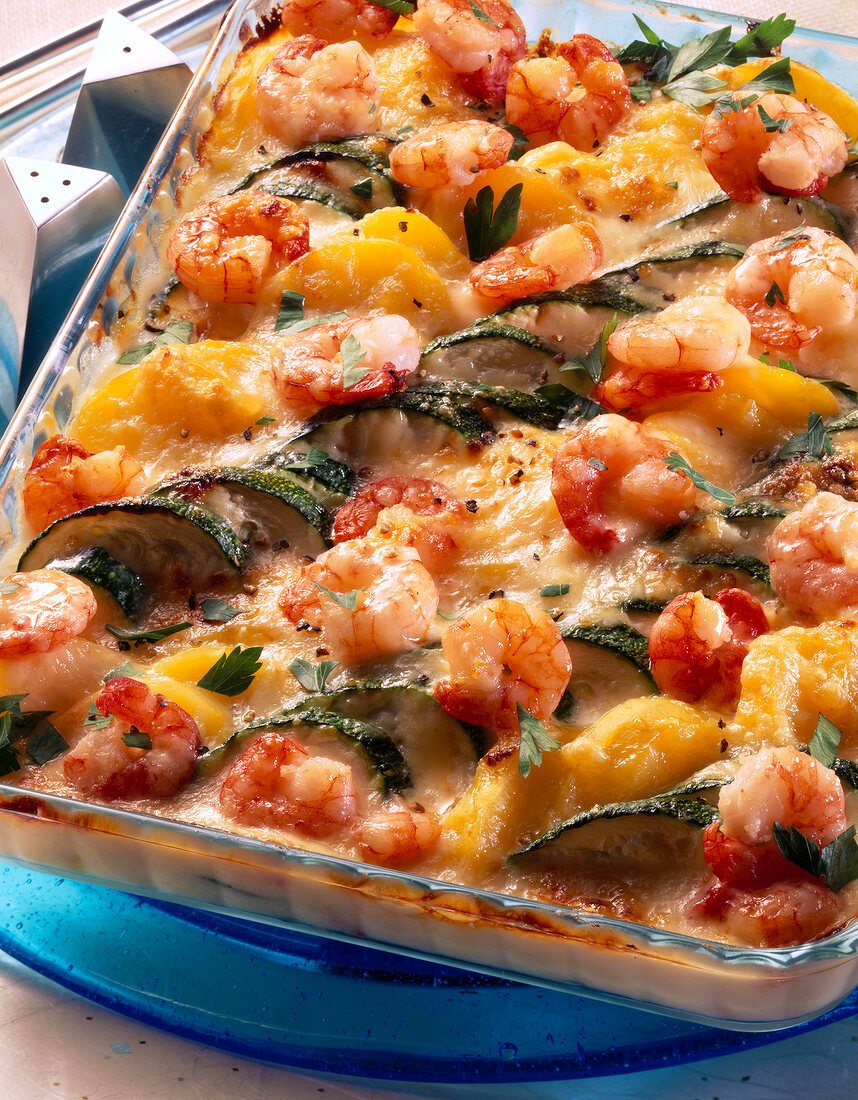 Close-up of shrimp and potato gratin with zucchini in glass baking tray