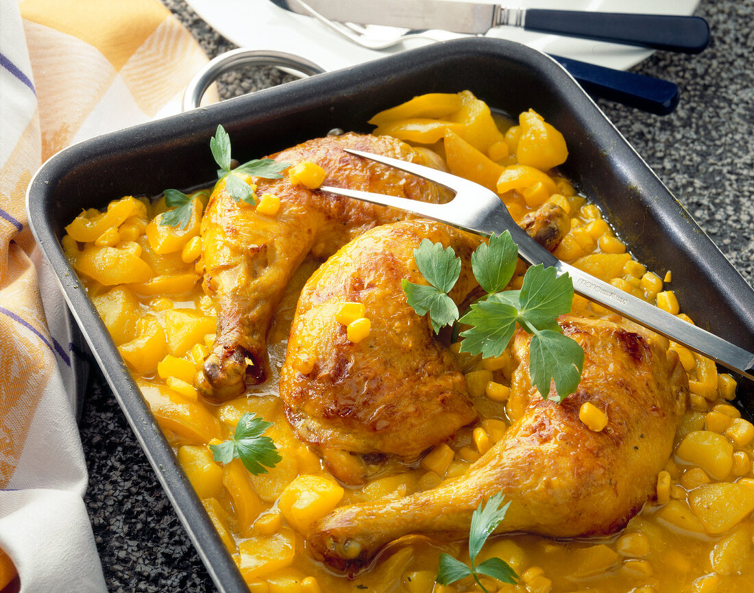 Braised chicken legs with corn and potatoes in baking dish