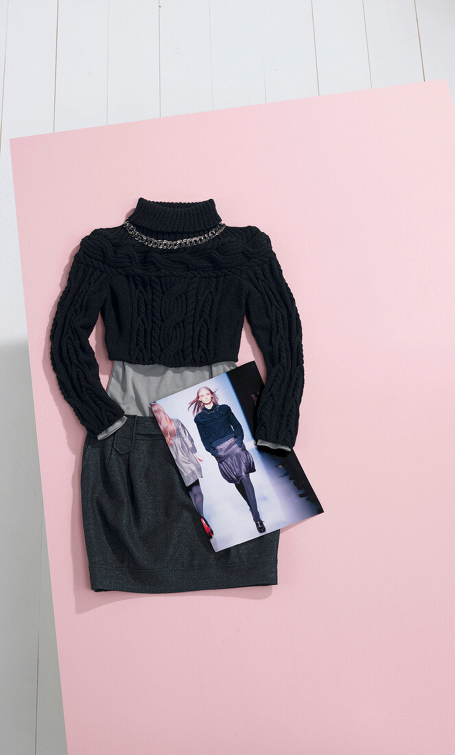 Close-up of black short sweater, knitted skirt and photograph