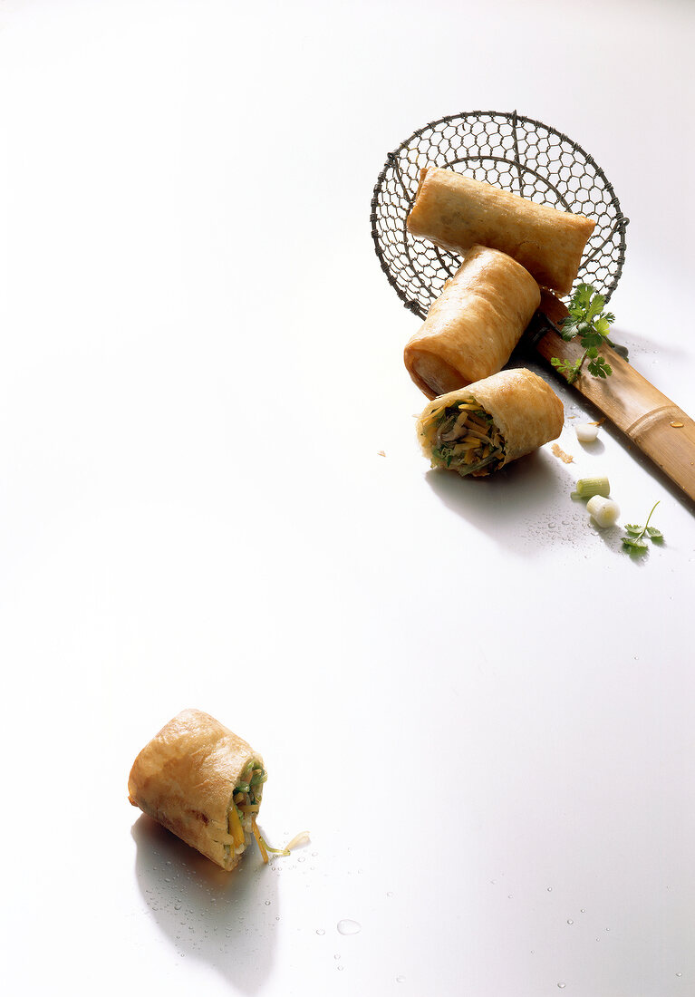 Spring rolls on ladle and white surface