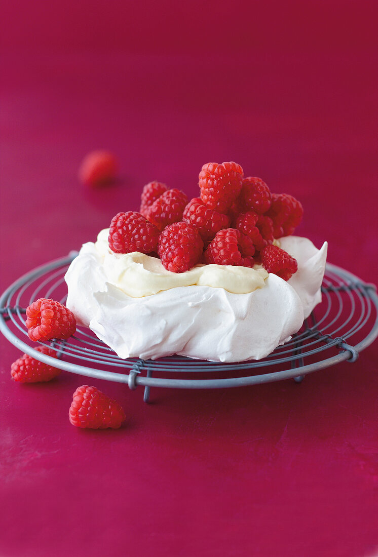 Himbeer-Pavlovas mit Mascarpone- Creme und Himbeeren, Hintergrund rot