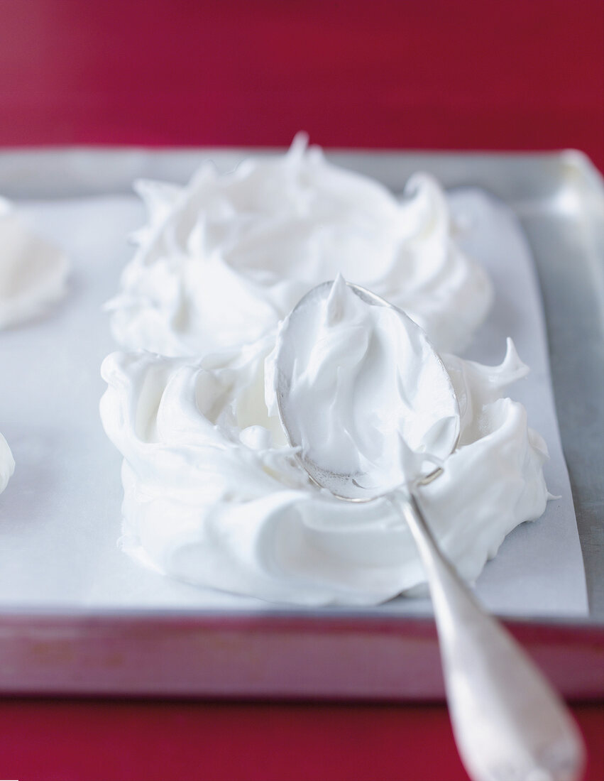 Spreading meringue on baking paper with spoon to raspberry pavlova