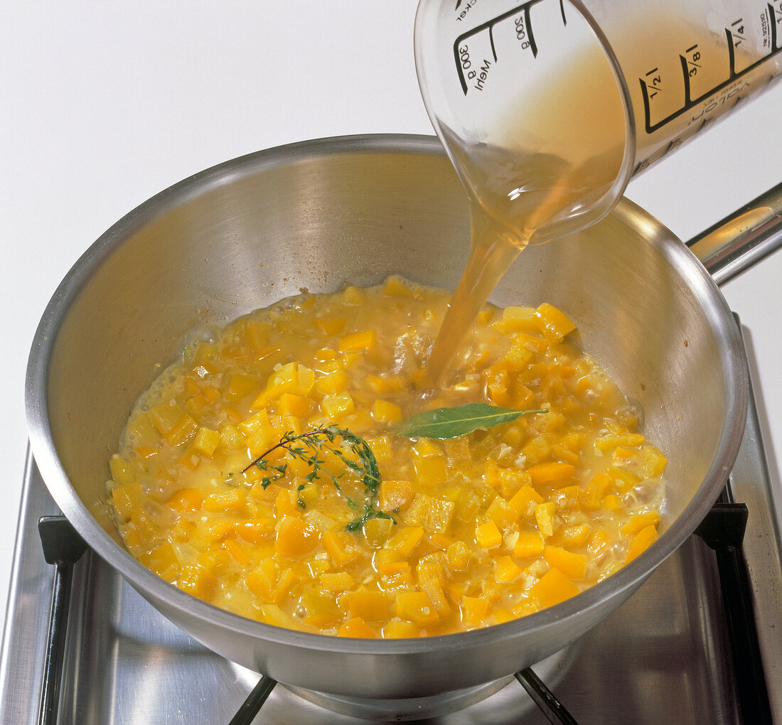 Adding stock to pumpkin mixture in pot, step 3