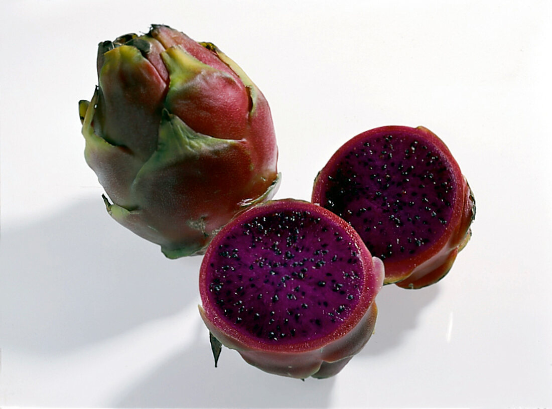 Scaly greenish red pitahaya with purple flesh on white background