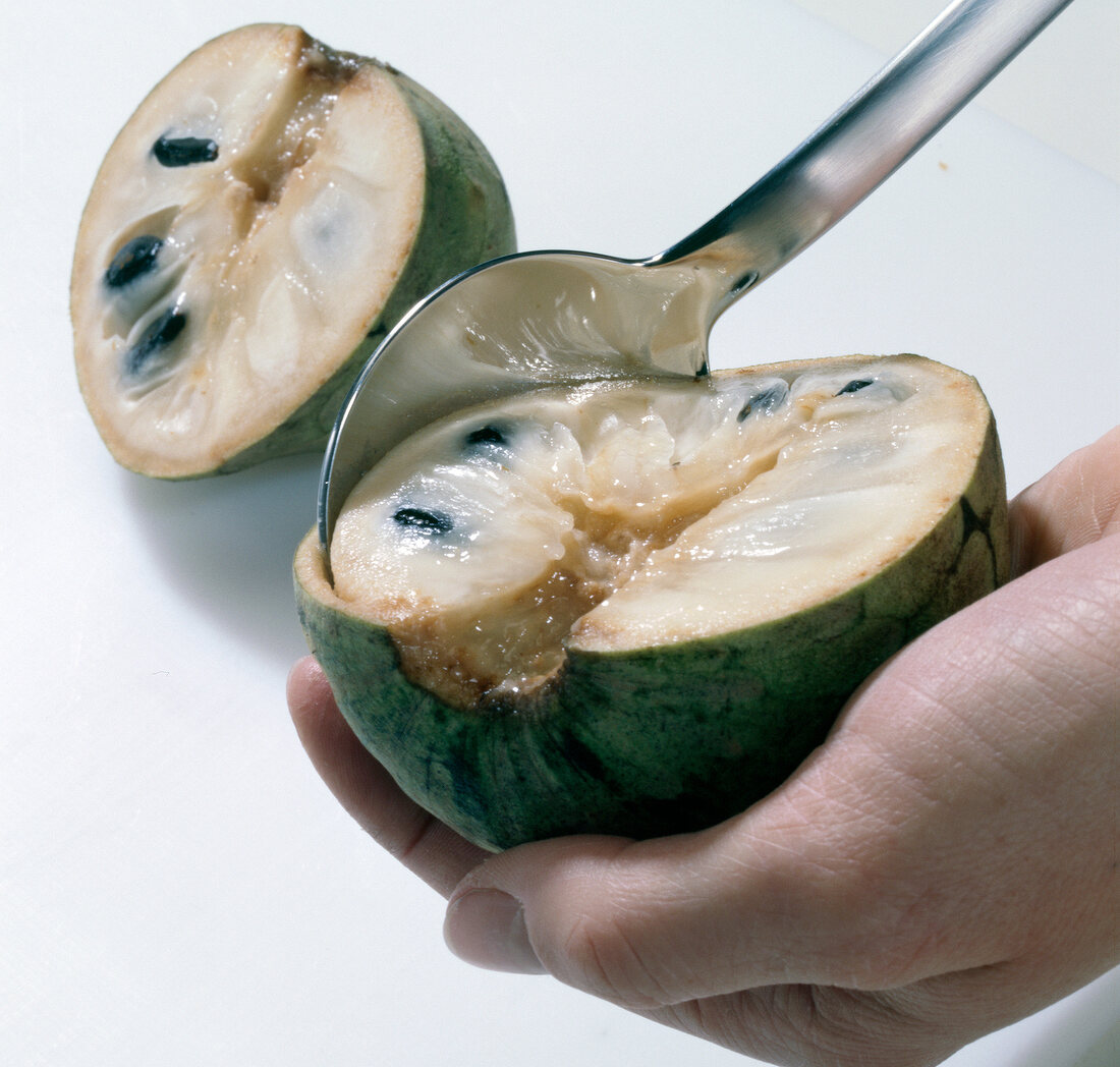 Scooping flesh of green custard apple with spoon, step 3