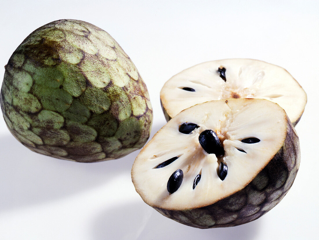 Whole and halved custard apple with white flesh and seeds