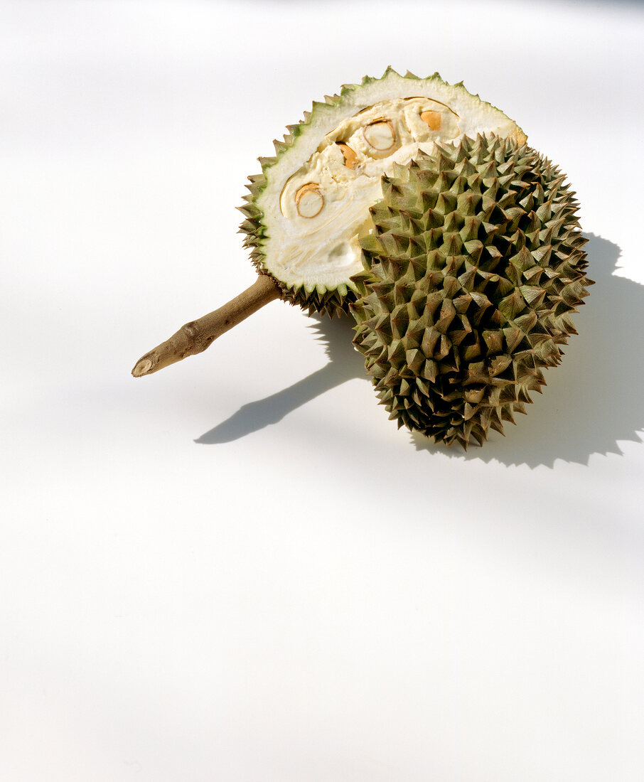 Halved spiny durian with white flesh on white background