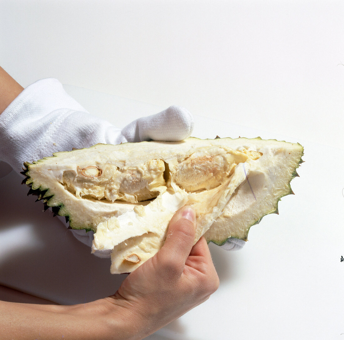 Close-up of man removing white pulp from durian