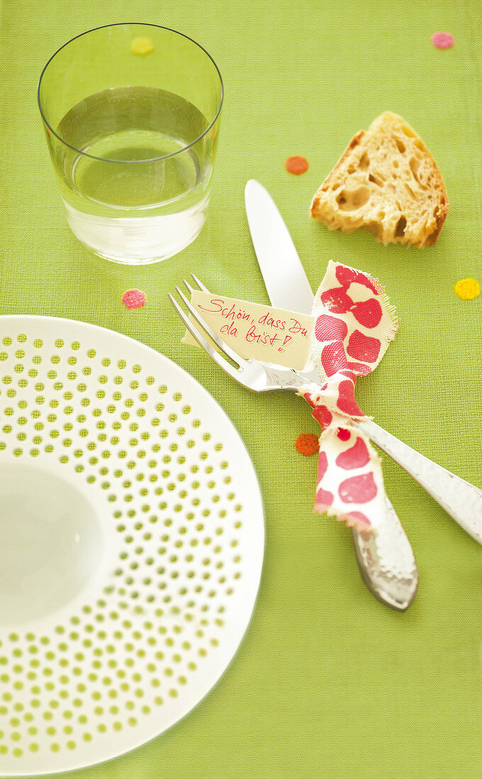 Close-up of silverware tied with polka dot ribbon and greeting