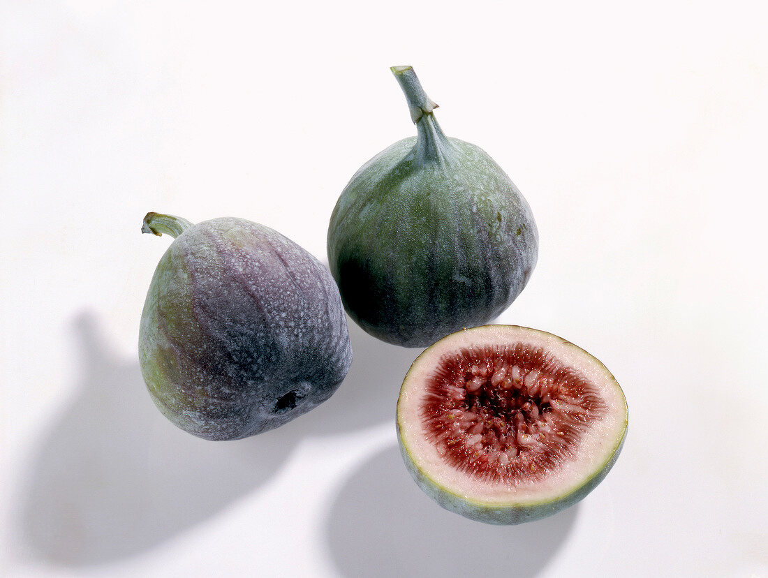 Whole and halved figs on white background