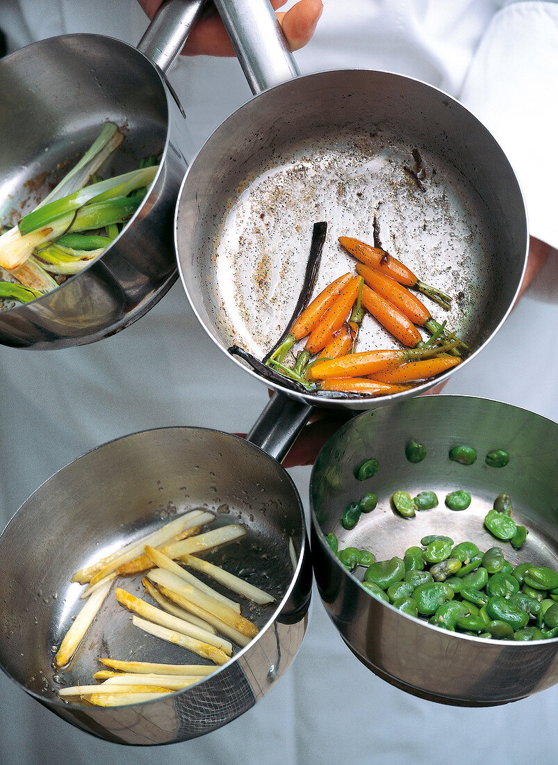 Cooked carrots, asparagus, beans and leeks in pots