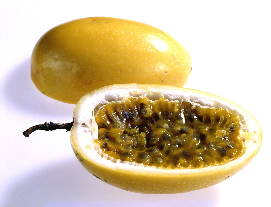 Whole and halved yellow passion fruit on white background