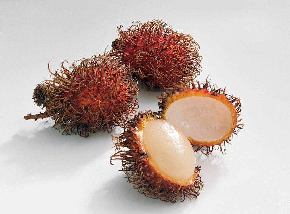 Whole and halved rambutan on white background