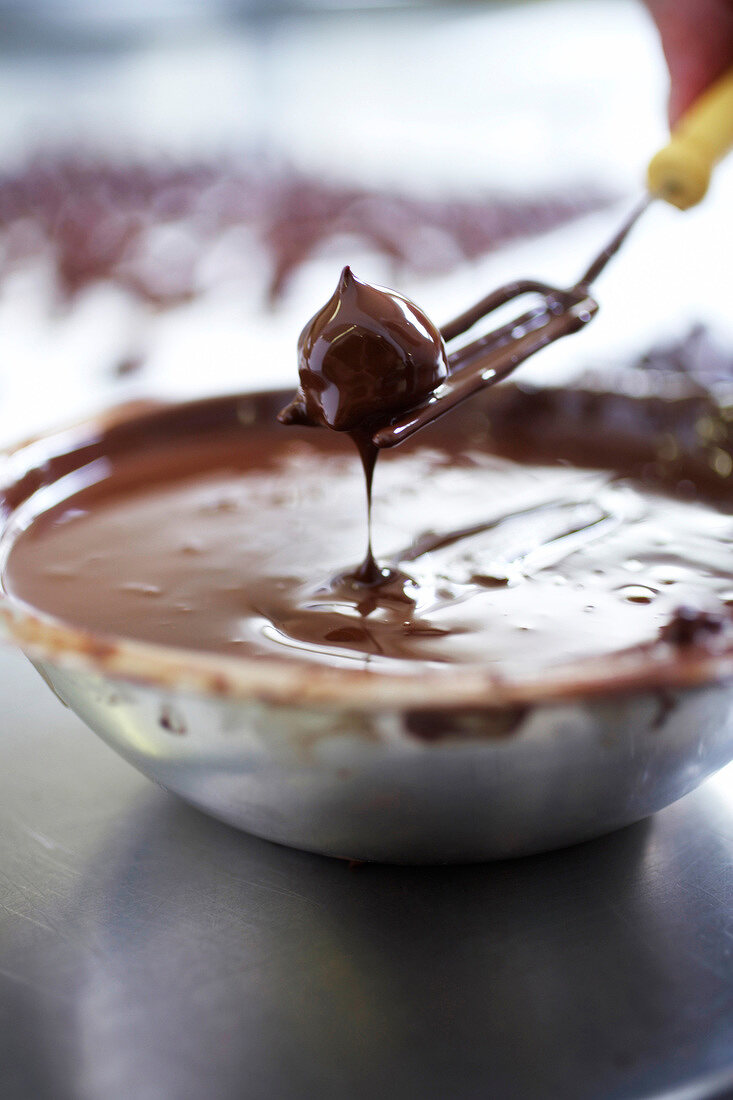 Chocolates balls being dipped in tempered chocolate