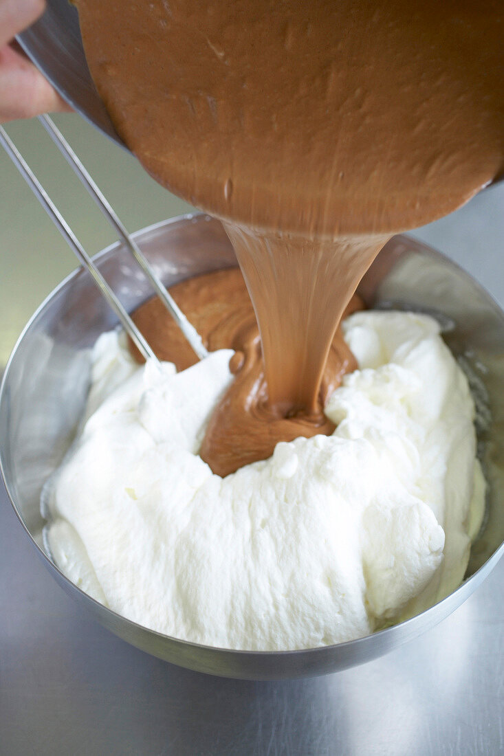 Melted chocolate being poured on whipped cream