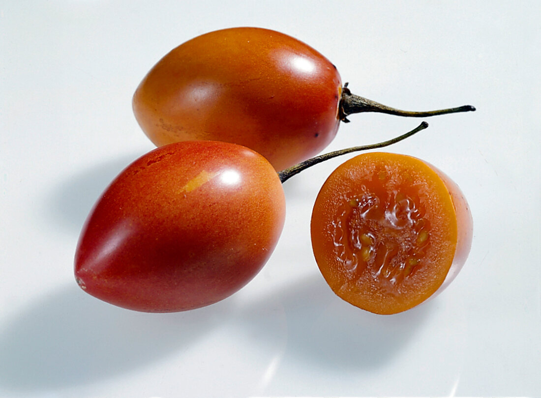 Whole and half tamarillo on white background