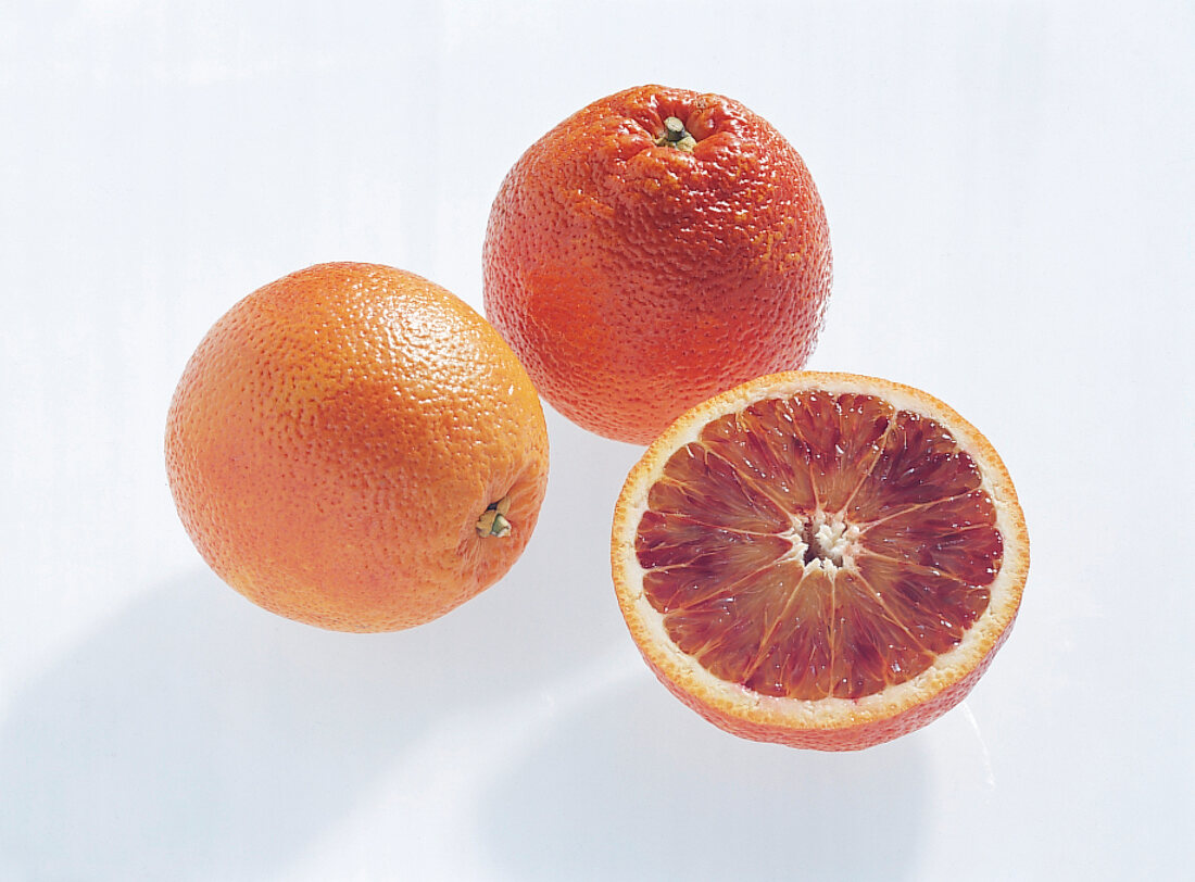 Whole and halved tarocco orange on white background