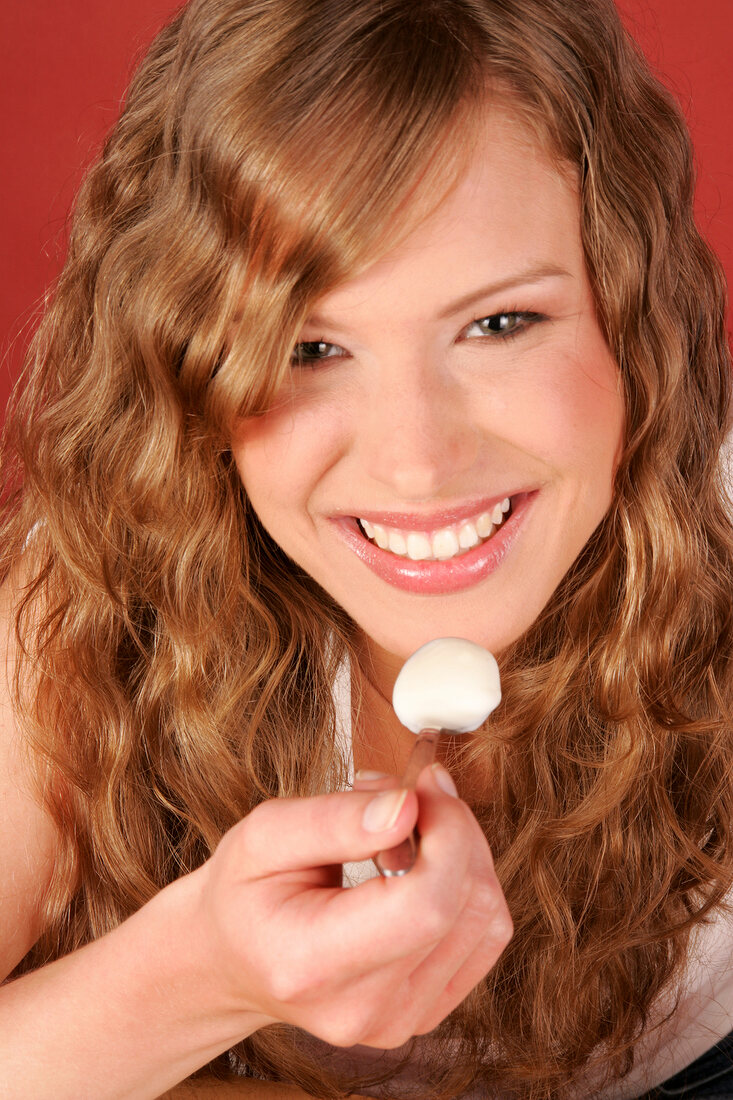 Close-up of woman having desert with spoon, smiling