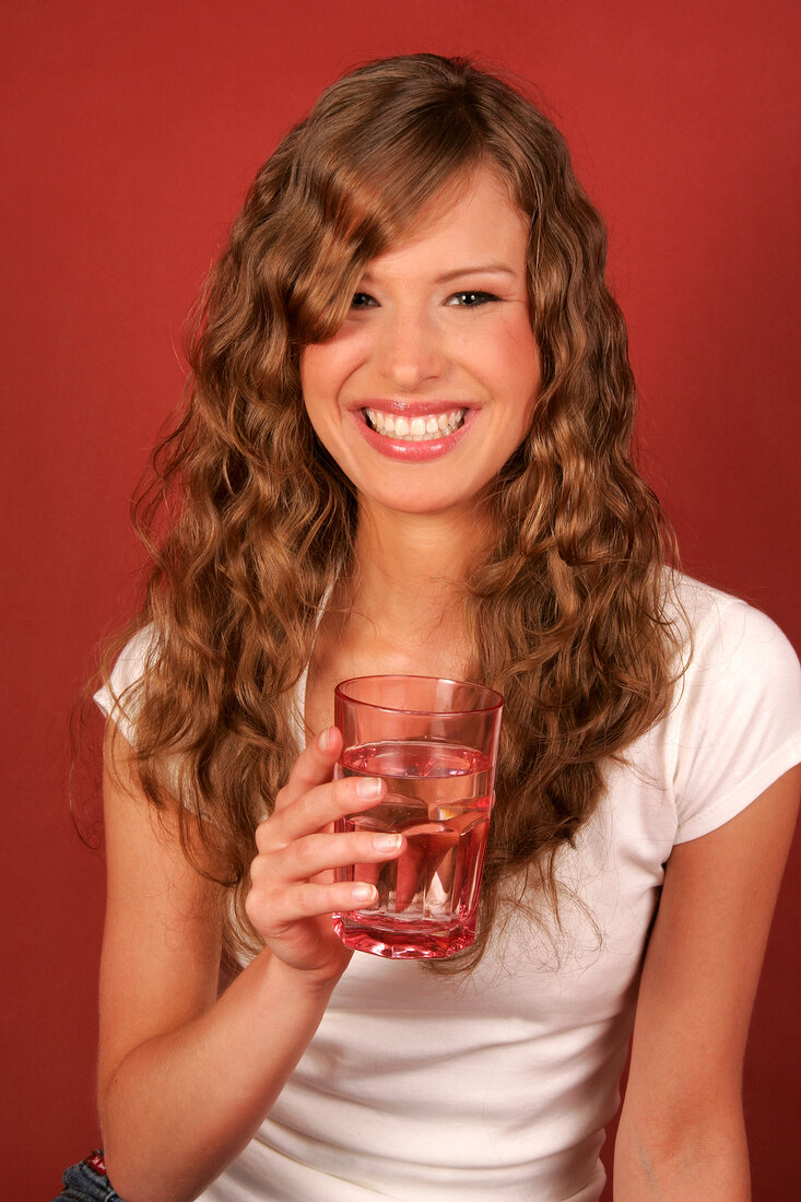 Sandra lacht und hält ein Glas Wasser in der Hand