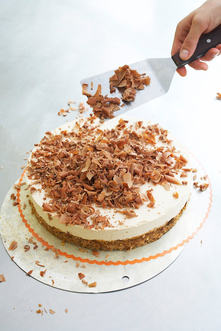 Close-up of chef spreading grated chocolate on walnut cake