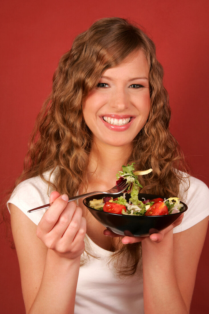 Frau hält Schale mit Salat und Gabel in der Hand