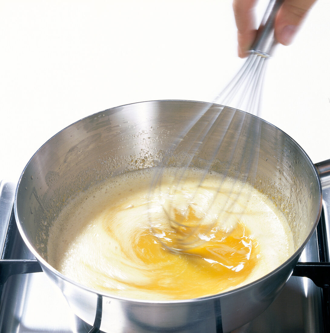 Hand whisking pineapple juice in lemon juice