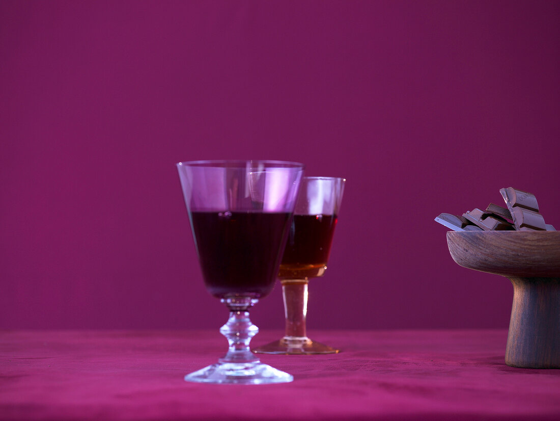 Zwei Gläser Rotwein und eine Holzschale mit Schokolade