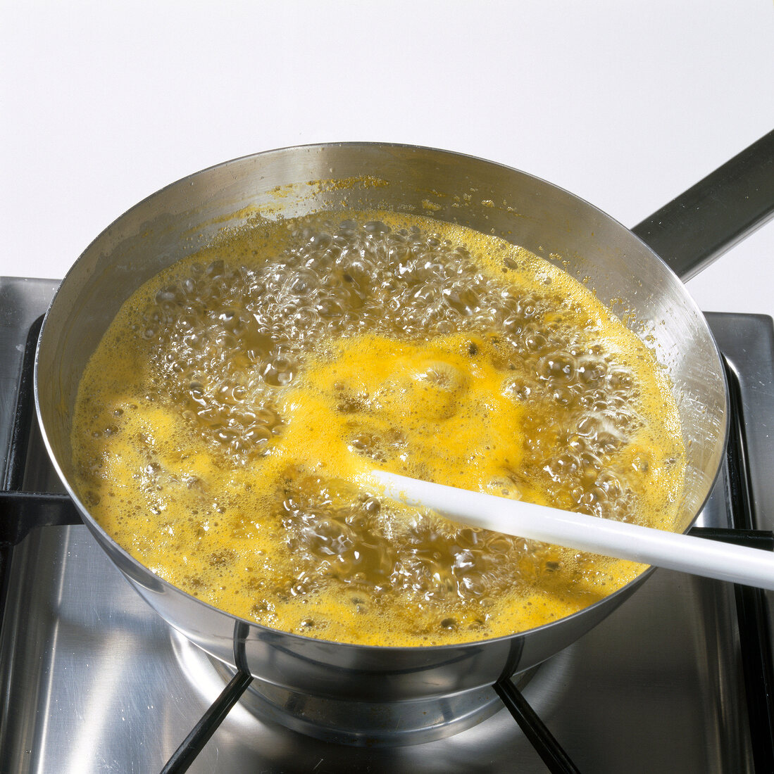 Passion fruit, tangerine juice and sugar being boiled in pot