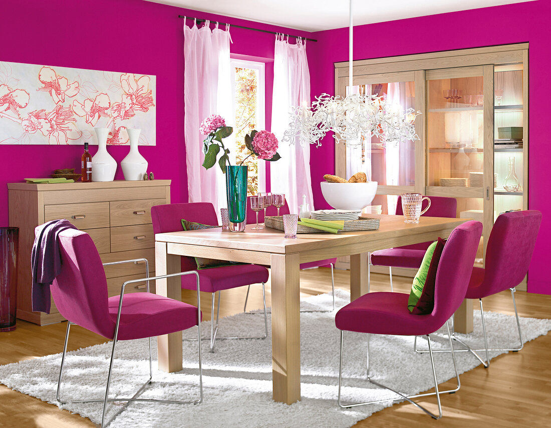 Dining room in pink with wooden furniture and green and white accessories