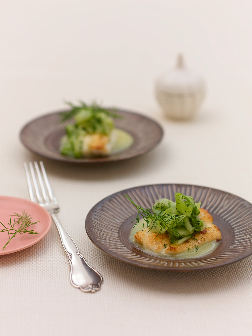 Sole fish with dill and cucumbers on plate