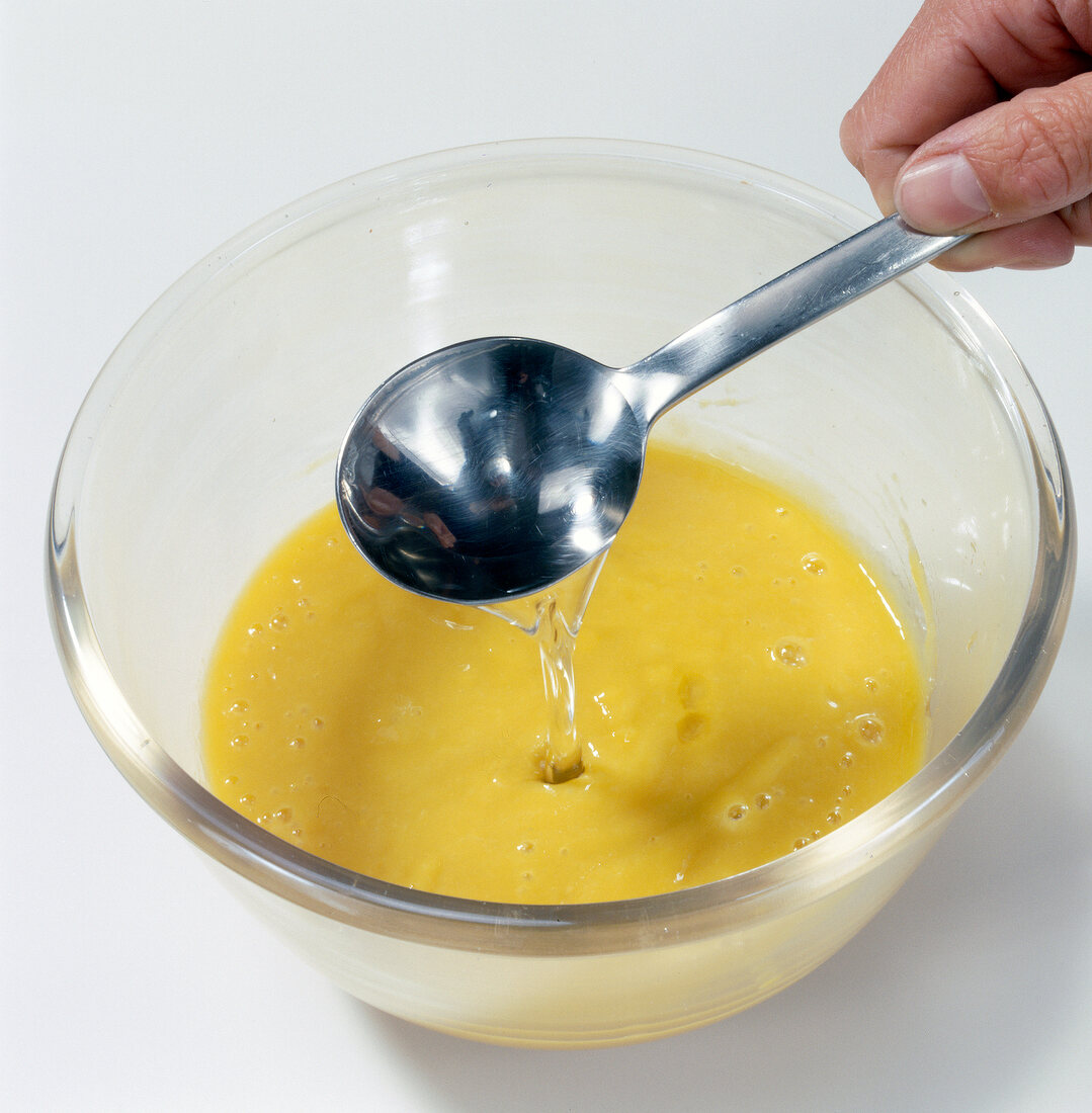 Sugar syrup being poured with spoon in mango puree