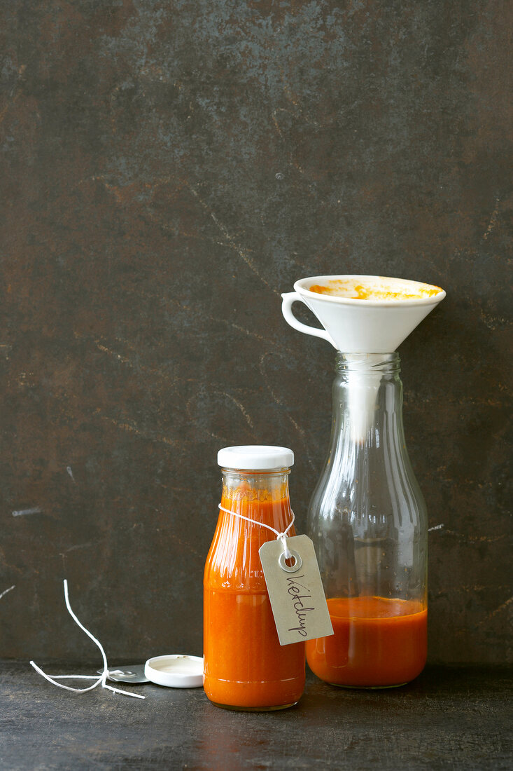 Tomato ketchup in glass bottle with funnel