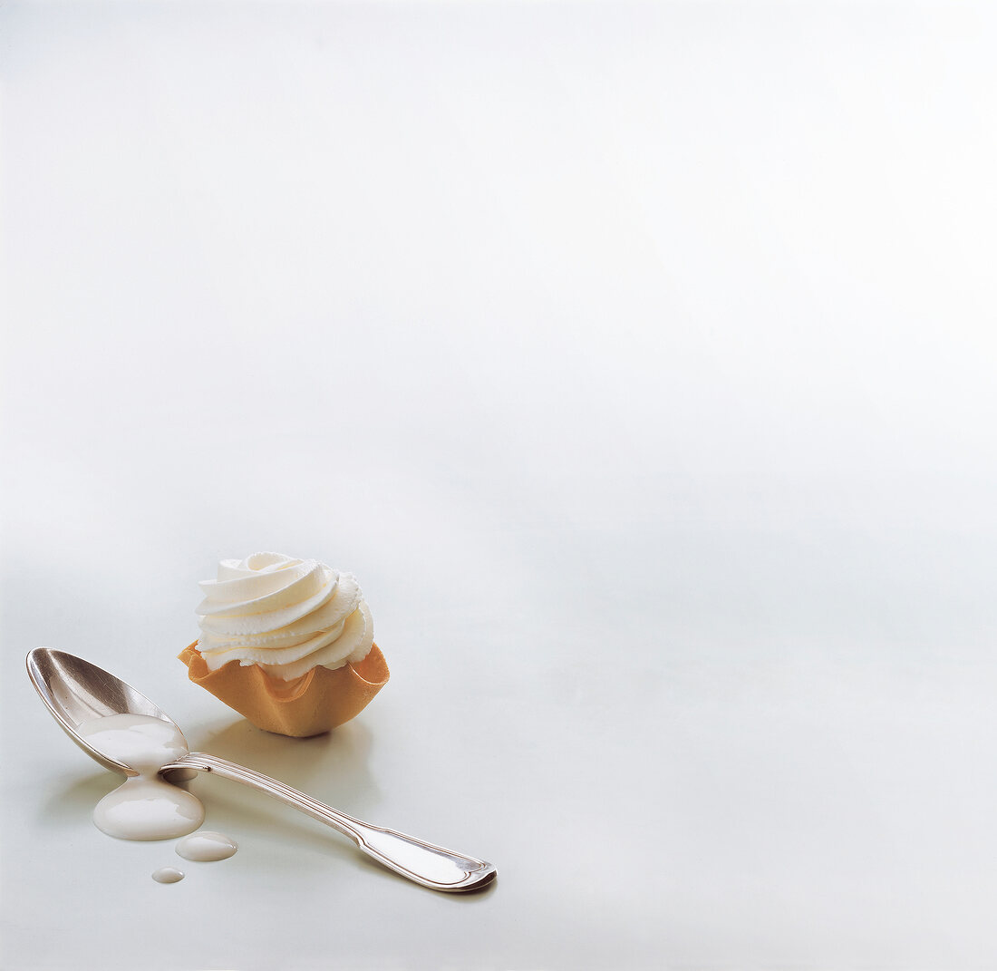 Whipped cream on dough mould and spoon on white background, copy space