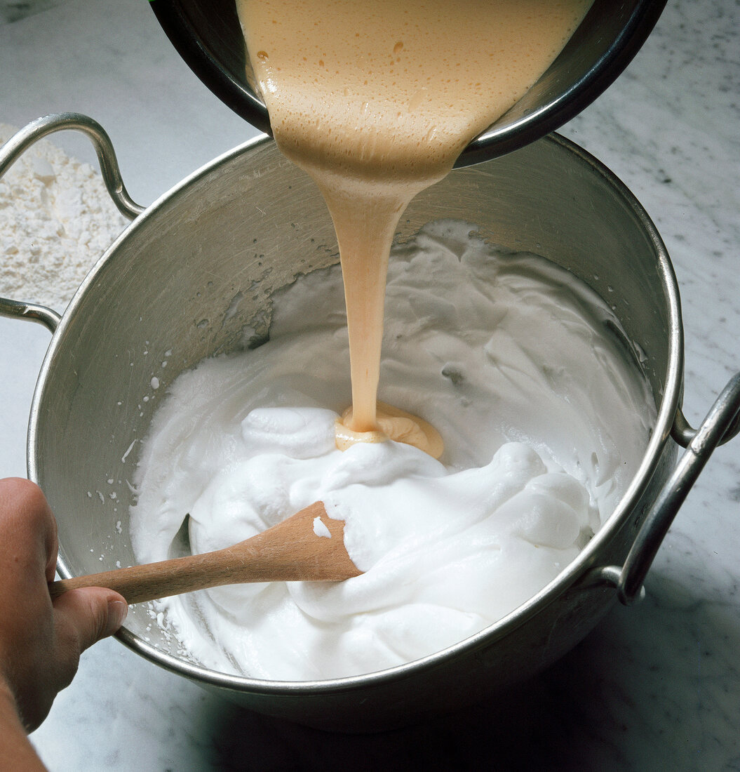 Pouring yolks in mixture for preparation of biscuit roulade, step 1