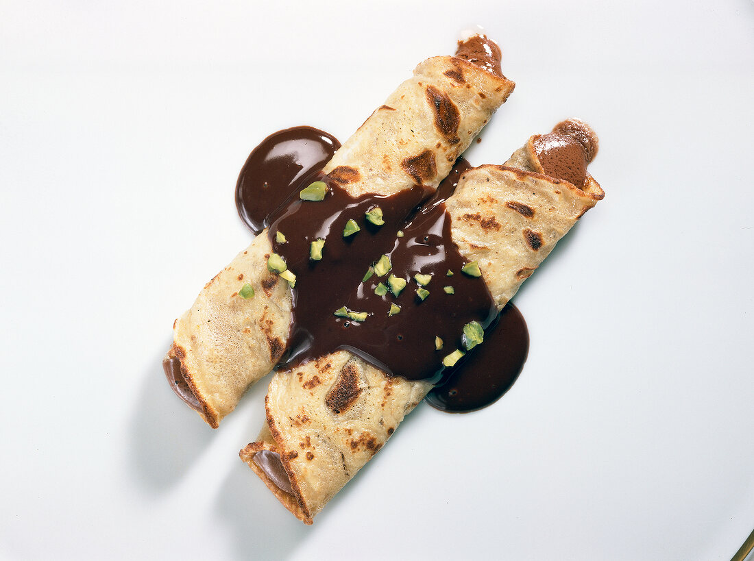 Crepes with chocolate cream on white background