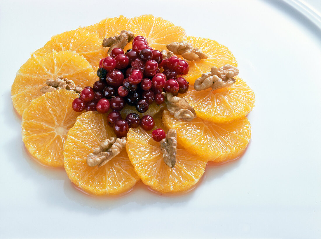 Oranges with cranberries and walnuts on white background