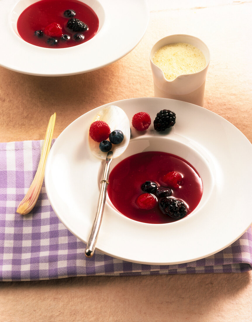 Beer cold soup with cinnamon foam and raspberries and blackberries on plates