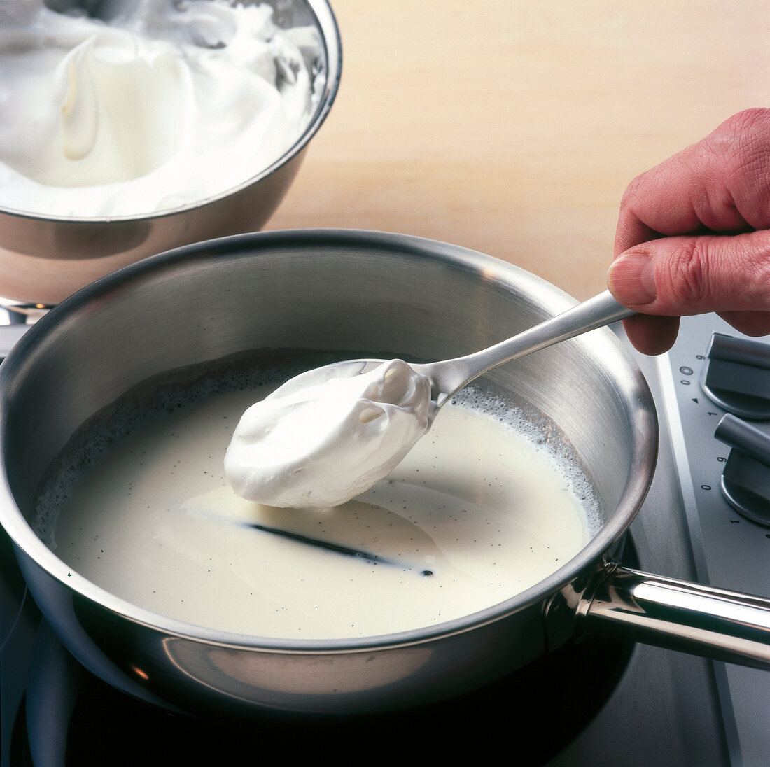 Egg white dumplings being poured in milk and vanilla for preparation of desserts, step 2