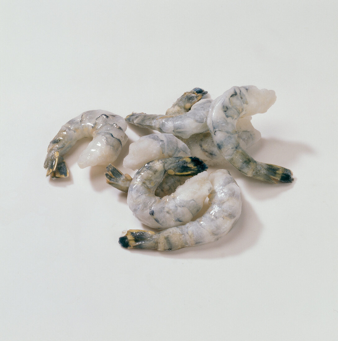 Close-up of peeled raw shrimps on white background