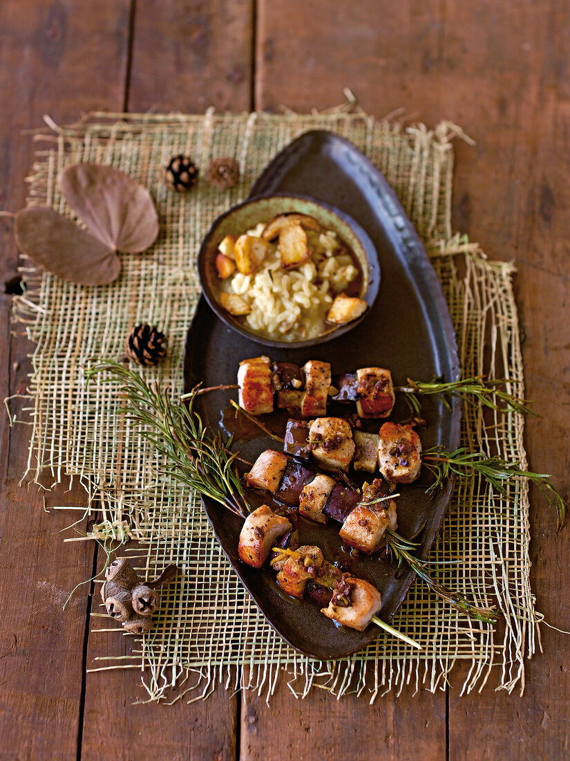 Rabbit kebabs with risotto on serving dish