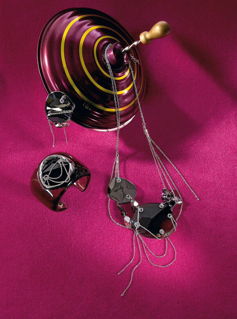 Necklace, brooch and bangle in black diamond crystals on pink background