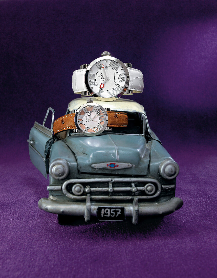 Toy car with two diamond watches on purple background