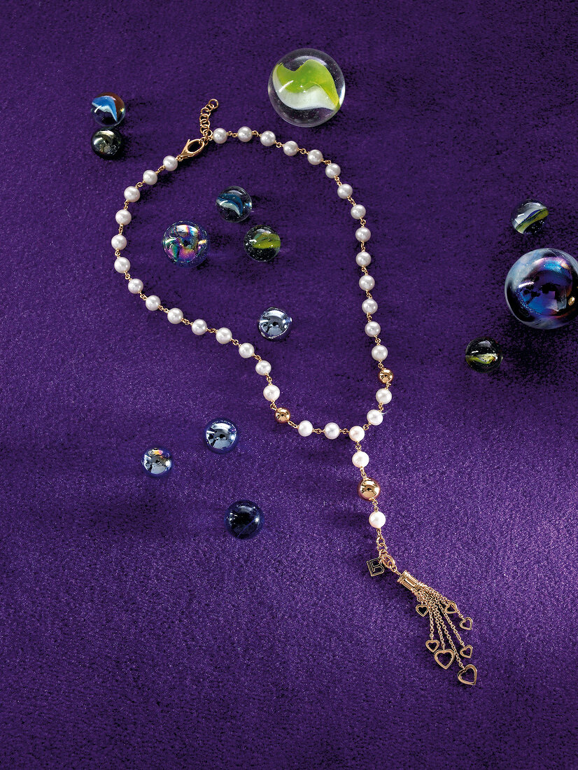 Kette aus Gold und Perlen auf lila Hintergrund