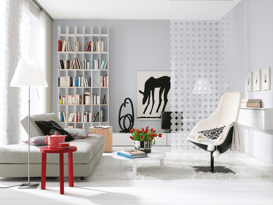 Living room in white with grey sofa, bookshelf, floor lamp and chair