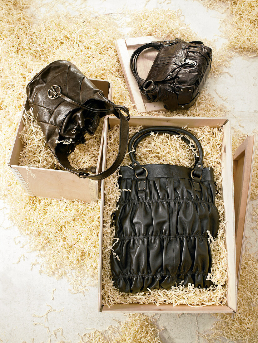 Three handbags in black on wood chips