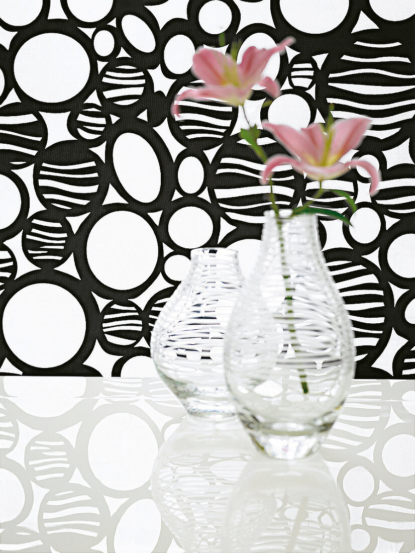 Glasvasen mit  Querstreifen vor Stoff mit Muster in Schwarz-Weiß