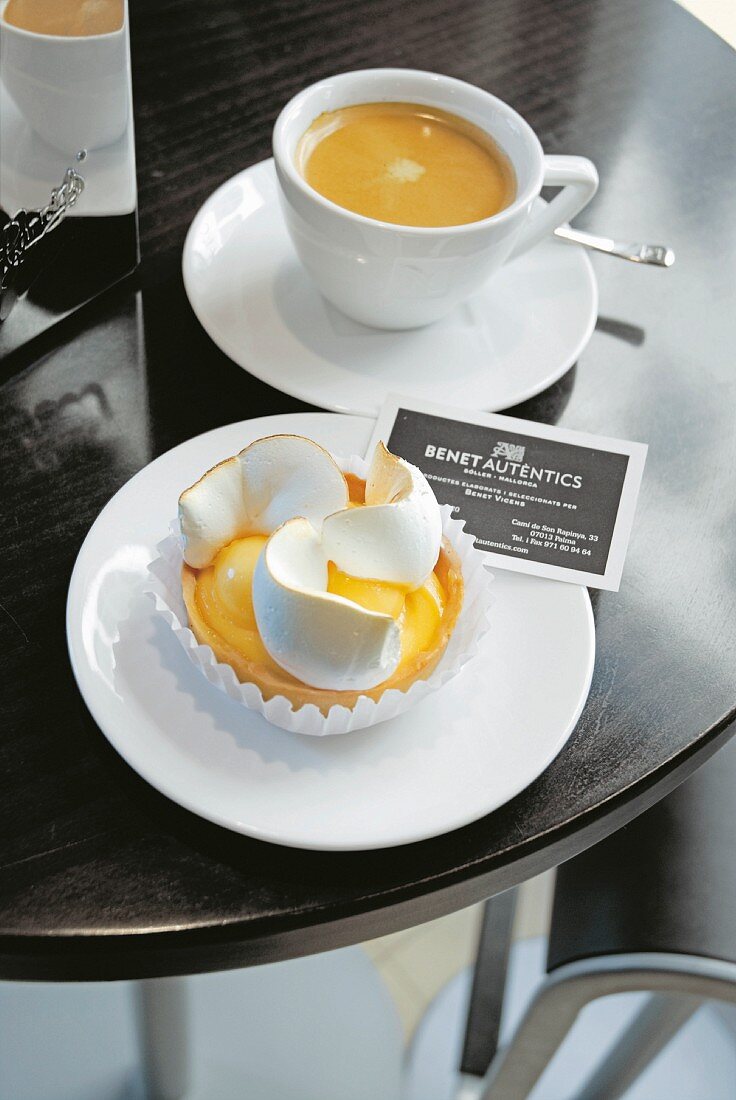 Lemon tart with meringue and coffee in a coffee shop